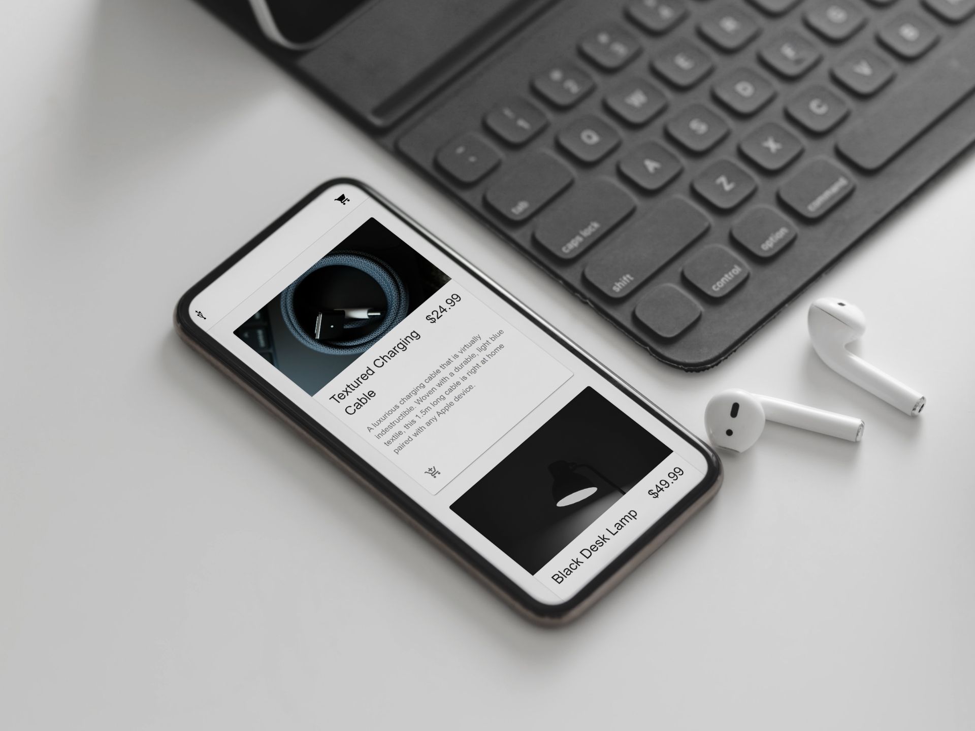 A close up of an iPhone and Airpods with a website open on the screen resting next to a tablet keyboard